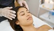 © fara - Relaxed woman receiving a head massage at a spa.  Image shows a close-up of a woman's face during a relaxing spa treatment.