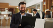 © peopleimages.com - Happy, businessman and laptop at hotel for travel, work trip or communication in lounge suite. Man, employee or traveler with computer or app for online business opportunity, career or accommodation