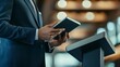 © Last - Businessman using tablet at a podium, preparing for a presentation.