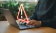 © Unlimited Resources - Person using laptop with warning sign alert online security risk