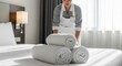 © Meow Creations - Hotel maid arranging fresh white towels on a clean bed in a modern hotel room