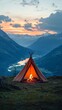 © Koja - A peaceful mountain campsite featuring a glowing campfire with a breathtaking sunset backdrop, surrounded by majestic peaks and valleys reflected in the river below.