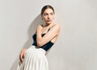 © Angelina Zhuravleva  - A stylish woman in a tennis skirt and black bodysuit poses leaning against a wall