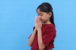 © ArvStd - Asian little girl praying to God with hands together. Isolated on blue background