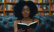 © IS-STUDIO - Woman with natural hair reads a book on a dark leather couch in front of a tall bookshelf