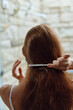 © SHOTPRIME STUDIO - Woman combing long brown hair in soft natural light, close-up rear view with blurred stone background creating calm and intimate atmosphere.