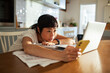 © Marko Geber - Frustrated woman laying her head on desk while holding phone and looking at laptop at home