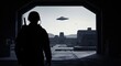 © dreamdes - Silhouette of a soldier observing a UFO flying above an alien complex, concept of military secret base and extraterrestrial invasion.