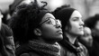 © Bhait - A contemplative individual with glasses and an afro, wearing a scarf, in a crowd setting.