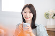 © kapinon - 部屋で飲み物を飲んでリラックスするかわいい若い女性　のんびりティータイム