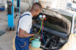 © Poguz.P - Mechanic with AC Refrigerant Manifold Gauge Set Repair Car Air Conditioning in Workshop, Technician Showing Thumbs Up and Check Car Air Conditioning System Refrigerant Recharge