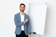 © luismolinero - Young caucasian man isolated on white background giving a presentation on white board and pointing to the side