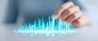 © STOCKJN - A hand interacts with a digital holographic interface displaying a futuristic blue data graph or soundwave visualization.