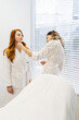 © dikushin - Vertical shot of beautician in white uniform explaining facial treatment procedure to female patient in bathrobe. Cosmetologist discussing aesthetic skincare treatment with client in beauty clinic.