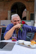 © Marino Bocelli - attractive middle-aged man with white hair showing a red rose during an outdoor aperitif