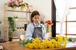 © Katcha - Female florist in apron writing details of order in notebook on the table while creating and making flower
