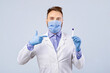 © Prostock-studio - Male doctor wearing protective mask and gloves, pointing at coronavirus PCR test tube on grey studio background. Physician holding vial for nasal and oral covid-19 diagnostic procedure