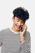 © SHOTPRIME STUDIO - Smiling man with curly hair talking on phone, wearing striped shirt, expressing happiness and joy in casual indoor setting with bright background.
