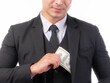 © suphaporn - A well-dressed businessman in a black suit discreetly placing US dollar bills into his jacket pocket, symbolizing financial transactions, savings, or perhaps a bonus