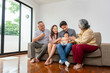 © Poguz.P - Happy Multi-Generational Family with Baby Smiling on Sofa, Joyful Grandparents, Parents, and Infant Bonding at Home, Asian Family Gathering Three Generations Sharing Laughter