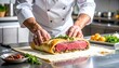 © Isman - Chef assembling Beef Wellington with duxelles and prosciutto on beef tenderloin, puff pastry on floured surface, hands at work in professional stainless steel kitchen — culinary precision in motion.