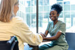 © zinkevych - Smiling african american doctor holding hand of her patient and looking friendly