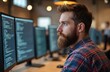© Vadym - Bearded IT specialist, programmer, looks at computer screen with code. Modern office interior. Man in checked shirt working with technology at workplace. IT engineer at work, solving coding tasks.