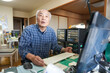 © Masakazu Tokashiki - In Japan, inside a small apartment room, a Japanese man in his late 70s sits in front of a computer, smiling and chatting, with warm indoor lighting creating a peaceful and homely atmosphere.