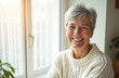 © Vadym - Happy elderly woman in sunlit room. Senior female smiles, enjoys peaceful morning at home. Calm, contented mature lady in cozy sweater. Portrait represents warmth, wisdom, positive attitude, active
