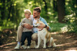 © standret - Positive facial expression, sitting. Father with son and dog are in the forest