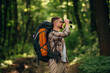 © standret - Side view, standing, holding binoculars. Male tourist is with backpack in the forest