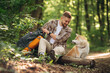 © standret - Tranquil, resting by sitting on the log. Man tourist is with his dog in the forest