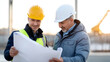 © Juiy - Two construction professionals, wearing safety helmets and reflective vests, are reviewing blueprint at construction site. setting is outdoors with blurred background of construction equipment