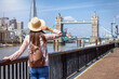 © moofushi - A tourist woman on a sightseeing tour looks at the Tower Bridge in London, England, during summer time