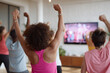 © Olena - Group fitness with virtual trainer. Diverse people exercising at home, following TV workout. Wellbeing, health, active lifestyle concept.