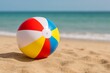 © woters - Colorful beach ball rests on sandy shoreline with blue ocean in background during sunny day