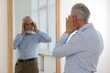 © New Africa - Handsome senior man looking at himself in mirror indoors