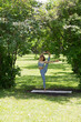 © ulza - Woman wearing yoga clothes praticing yoga and stretching  on a sunny day in nature. Healthy lifestyle concept. solo outdoor activities. yoga coach leads master class in park