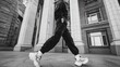 © Lumi_Studio - Dynamic street style capture of a model mid-stride in monochrome activewear and chunky sneakers, framed by urban architecture