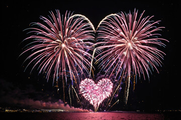 Wall Mural - A heart-shaped firework explodes in the night sky above a calm body of water, creating a romantic and magical atmosphere