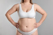 © New Africa - Weight loss. Plus size woman in underwear on gray background, closeup