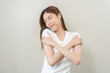 © KMPZZZ - Smiling positive, hug self care happy asian young woman hands hugging herself shoulders, enjoy yourself, self love and self care, smile girl face expression self esteem standing isolated on background