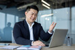 © Tetiana - Dissatisfied young Asian male businessman sitting at desk in office and looking at laptop gesturing with hand