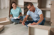 © New Africa - Happy couple assembling furniture on floor at home
