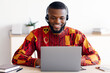 © Prostock-studio - Distance Education. Smiling Black Man In African Shirt And Headset Watching Webinar On Laptop At Home, Having Online Lesson, Positive Millennial Guy In Ethnic Costume Sitting At Desk With Computer