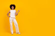 © Anastasiya - Check This. Positive cheerful beautiful young african american female in white outfit showing copy space for advertisement, happy black female standing over yellow studio background, full length shot