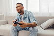 © SHOTPRIME STUDIO - Joyful man enjoying a video game while relaxing at home, reflecting a moment of serenity and digital detox from everyday stress and work-life blur.