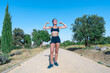 © Juan Pedro Peña - Mujer deportista haciendo gesto de soy fuerte, un día soleado con cielo azul en el parque.