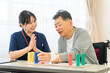 © buritora - 介護施設・リハビリ施設で働く作業療法士の職員とリハビリをするシニア男性