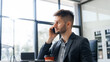 © Phushutter - A smart Caucasian businessman sits confidently at desk in modern indoor office, using laptop for online consulting, showcasing professionalism, success, digital expertise in corporate environment.